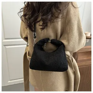 Détail d'un sac seau en polaire noire porté avec un manteau classique en laine kaki