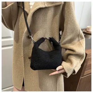 Détail du sac seau noir en fausse fourrure avec bandoulière sur un manteau de chameau
