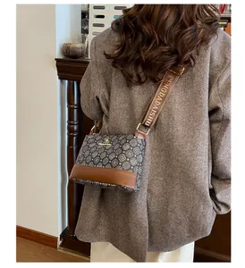 Close-up of vintage patterned crossbody bag with tan leather trim and wide fabric strap
