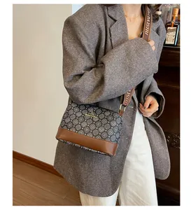 Detail showing the retro patterned bucket bag with wide brown leather strap on a model