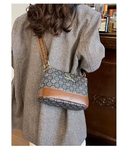 Detail of printed bucket bag with wide strap worn over a grey herringbone coat