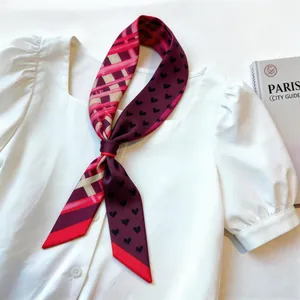 Elegant red twilly silk scarf with heart pattern tied on a white puff sleeve shirt