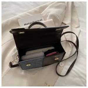 Detail of mixed-media handbag featuring grey wool and brown leather with magnetic buckle