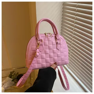 Close-up of pink shell bag featuring textured checkerboard pattern and gold hardware