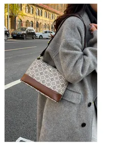 Close-up of beige printed crossbody bag featuring kangaroo logo and dark brown leather base