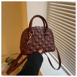 Detailed view of dark brown shell bag with embossed checkerboard pattern and gold hardware
