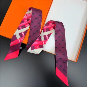 Detailed view of striped silk twilly scarf with heart dots on a luxury orange gift box