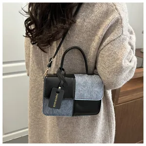 Detailed back view of a stylish grey tweed and black leather patchwork crossbody bag