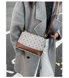 Detail of crossbody bucket bag with geometric patterns and brown leather accents