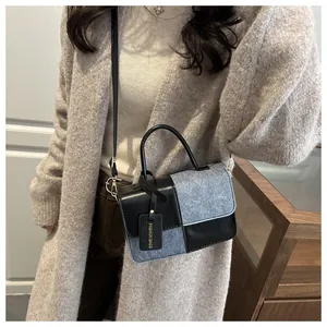 Detail of a chic patchwork tote bag with black leather and grey fabric texture on a model