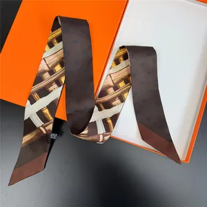 Close-up of elegant brown silk twilly with bamboo weave pattern inside a classic orange gift box