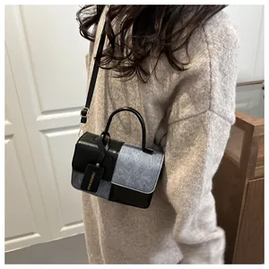 Fashionable black and grey color-block crossbody bag styled on shoulder with a hang tag