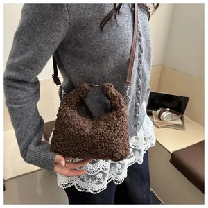 Gros plan sur un sac seau en laine marron foncé avec bandoulière en similicuir réglable