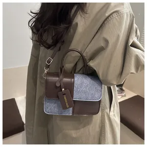 Detail of a patchwork shoulder bag with leather handles and adjustable metal buckle strap