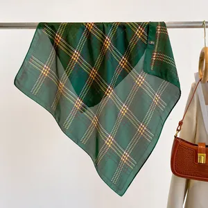Detailed view of dark green plaid silk scarf draped elegantly with a fashion handbag