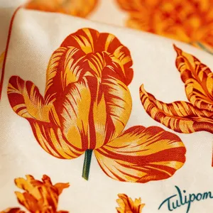 Detailed macro shot of premium twill silk scarf featuring vibrant orange tulip prints