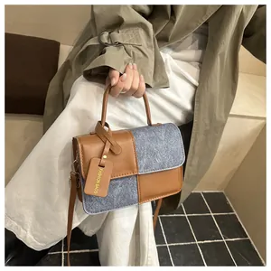 Detail of the brown faux leather and grey denim patchwork tote bag with fashion tag