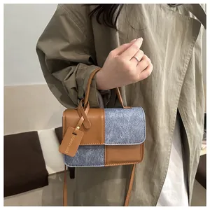 Detail of color-block patchwork handbag in brown leather and grey wool texture fabric
