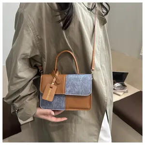 Detail of a brown and grey textured patchwork crossbody bag with a fashion tag