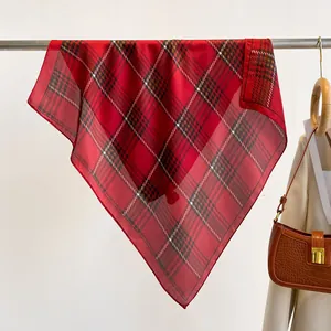 Classic red plaid silk scarf draped elegantly with a beige blazer and leather handbag