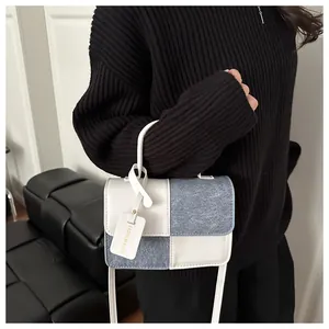 Detail of color-block handbag showing beige leather and blue denim patchwork texture