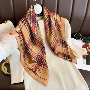 Detail of green and red plaid square silk scarf styled with beige knit sweater