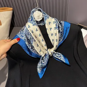 Close-up of blue and white satin square scarf with paisley patterns tied on a black sweater