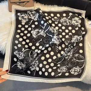 Macro detail of a 70cm satin silk scarf with black polka dots and white floral patterns