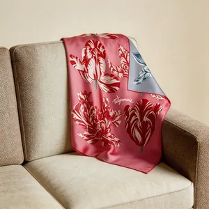 Pink silk square scarf with red tulip prints draped on a beige textured sofa armrest