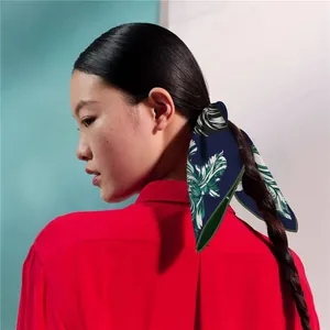 Detail of a navy blue floral silk scarf styled as a hair accessory on a braided hairstyle