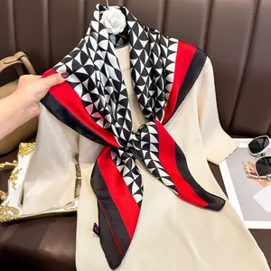 Detail of red and black geometric satin square scarf styled on a beige sweater