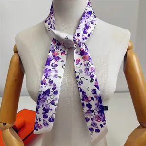 Détail d'un foulard en soie twilly à imprimé floral avec motifs abstraits et étiquette