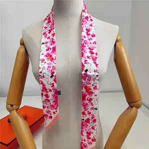 Gros plan d'un foulard en soie rose à fleurs noué sur la main d'un mannequin en bois