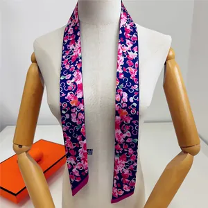 Détail d'un foulard étroit en soie à fleurs sur un mannequin pour cheveux et sacs