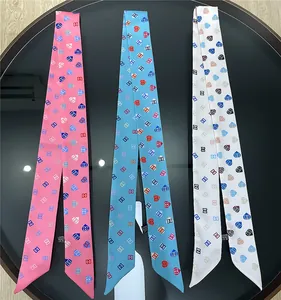 Details von drei Twilly-Schals auf schwarzem Tisch mit Materialzusammensetzung und Pflegeetikett
