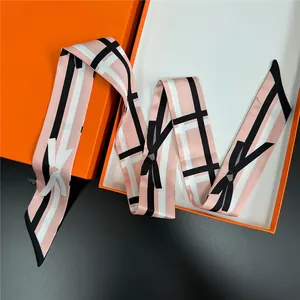 Pink bow tie scarf with checkered patterns displayed on a premium orange gift box
