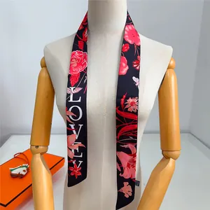Dettaglio di sciarpa in seta con stampa floreale e scritta Lovely su un manichino