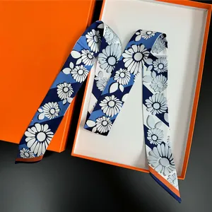 Detalle de pañuelo de seda con estampado de margaritas en una caja de regalo naranja