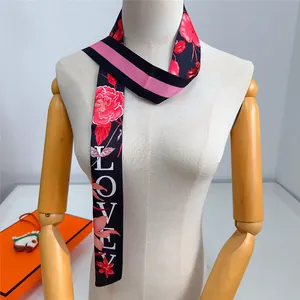 Dettaglio di un foulard twilly lungo con motivo floreale rosso e scritta LOVE sul manichino