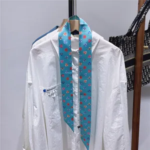 Detail eines blauen Twilly-Schals aus Seide mit geometrischem Logo-Muster an Hemd