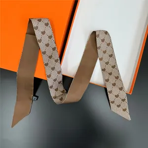 Vista macro di foulard Twilly con motivo floreale a cuore, texture seta e etichetta cura