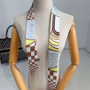 Dettaglio di una lunga sciarpa di seta con motivo a scacchi marrone e design geometrico