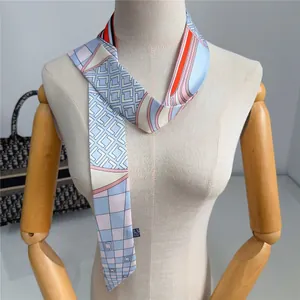Elegante foulard lungo in seta a motivi geometrici annodato sul manico di una borsa