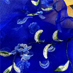 Vista macro di sciarpa in seta blu con ricami floreali e motivi a foglia pregiati