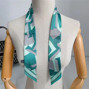 Detail van een geometrische twilly sjaal van kunstzijde met mintgroene patronen op pop