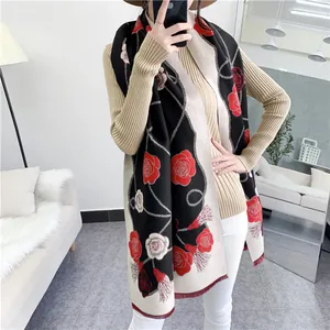 Détail de l'écharpe à motif camélia avec roses rouges et pompons élégants