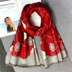 Détail de l'écharpe d'hiver rouge avec motifs de roses grises et fines franges délicates