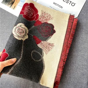 Détail d'une écharpe fleurie avec texture cachemire et finitions à franges rouges