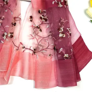 Dettaglio del ricamo floreale su uno scialle in seta e lana rosa sfumato elegante