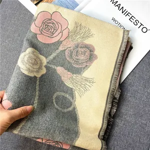 Gros plan d'une écharpe d'hiver avec motifs roses, maille épaisse et détails à franges
